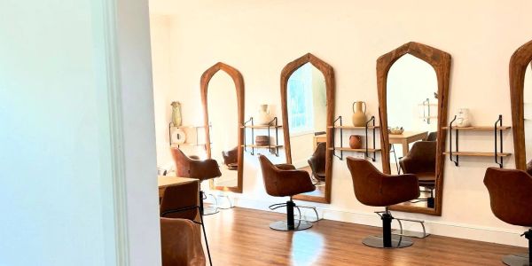 Modern hair salon with brown chairs and tall mirrors.
