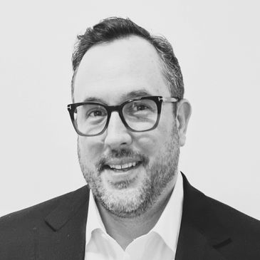 Smiling man with glasses in a suit, black and white photo.