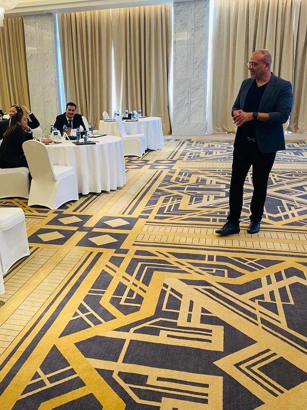 A man standing in front of seated people in a conference room.