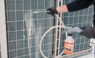 HVAC Technician cleaning a condenser coil