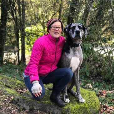 Woman in pink jacket with large black and white dog outdoors.