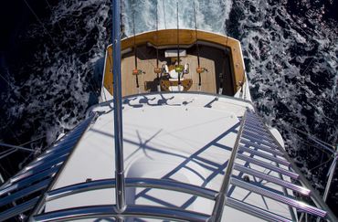 View from the top of a fishing boat with fishing rods and water wake.