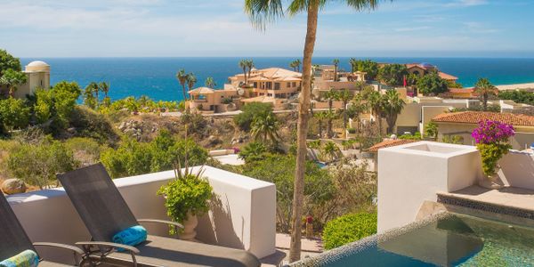 Ocean view from a luxurious patio with lounge chairs and a small pool.