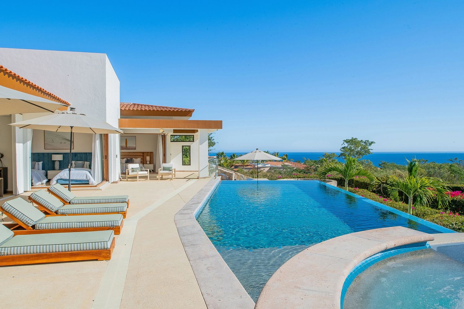 Luxury villa with infinity pool overlooking the ocean under a clear blue sky.
