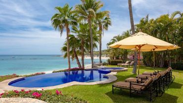 Tropical poolside with lounge chairs and ocean view.