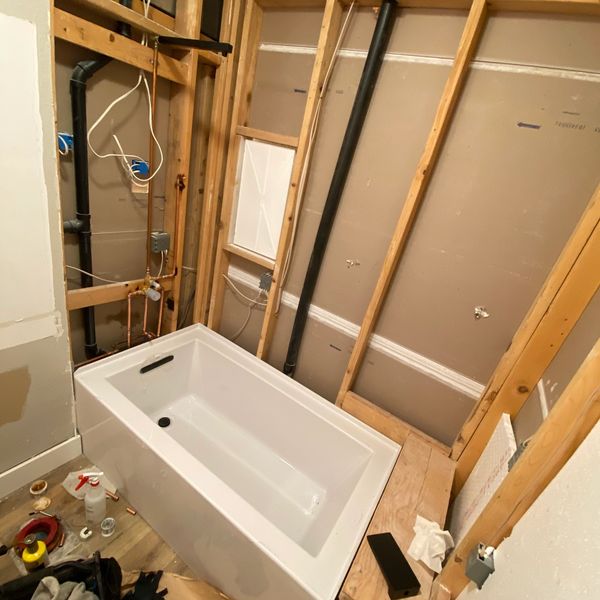 Bathtub installation in progress within unfinished bathroom walls.