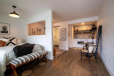Cozy studio apartment with a bed, small kitchen, and seating area.