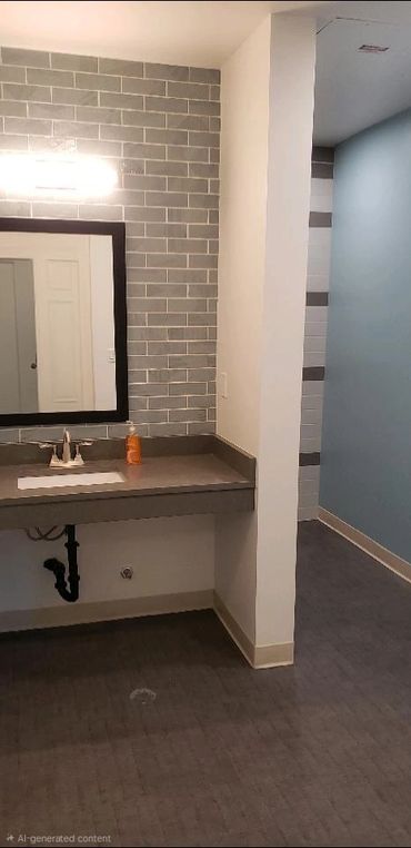 Modern bathroom sink area with gray tiles and a large mirror.