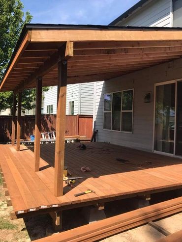 Newly built wooden deck with a shaded pergola attached to a house.