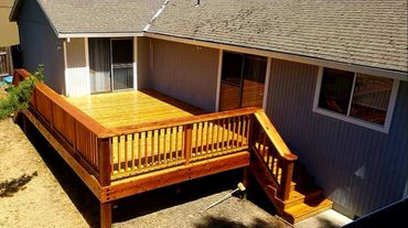 Newly built wooden deck attached to a house, shining under sunlight.