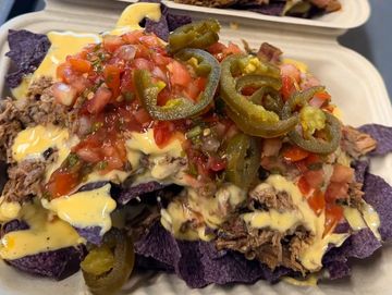 Loaded nachos with cheese, pulled pork, jalapeños, and salsa.