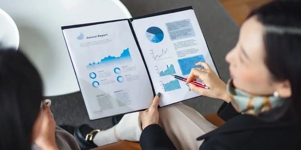 Two people reviewing an annual report with charts and graphs.