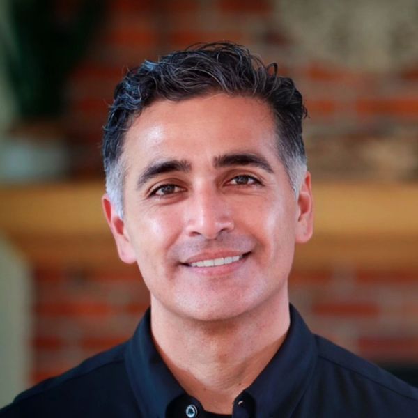 Smiling man with dark hair in a black shirt.