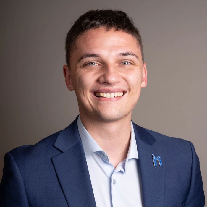 Mike Gombita with a navy suit, light blue button-down shirt, and a Misericordia University pin.