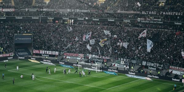 Crowded football stadium with fans and players near goalpost.