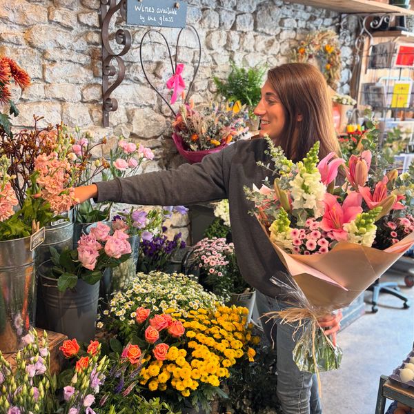 Woman arranging flowers in a cozy flower shop with a bouquet in hand.