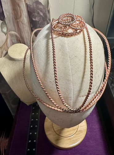 Copper twisted wire jewelry displayed on mannequin heads.