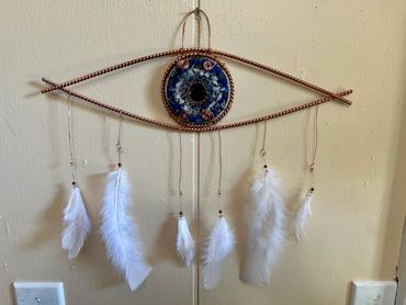 Handcrafted wall hanging with white feathers and a blue circular centerpiece.