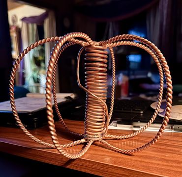 Intricate copper wire sculpture with twisted loops and coils on a wooden surface.
