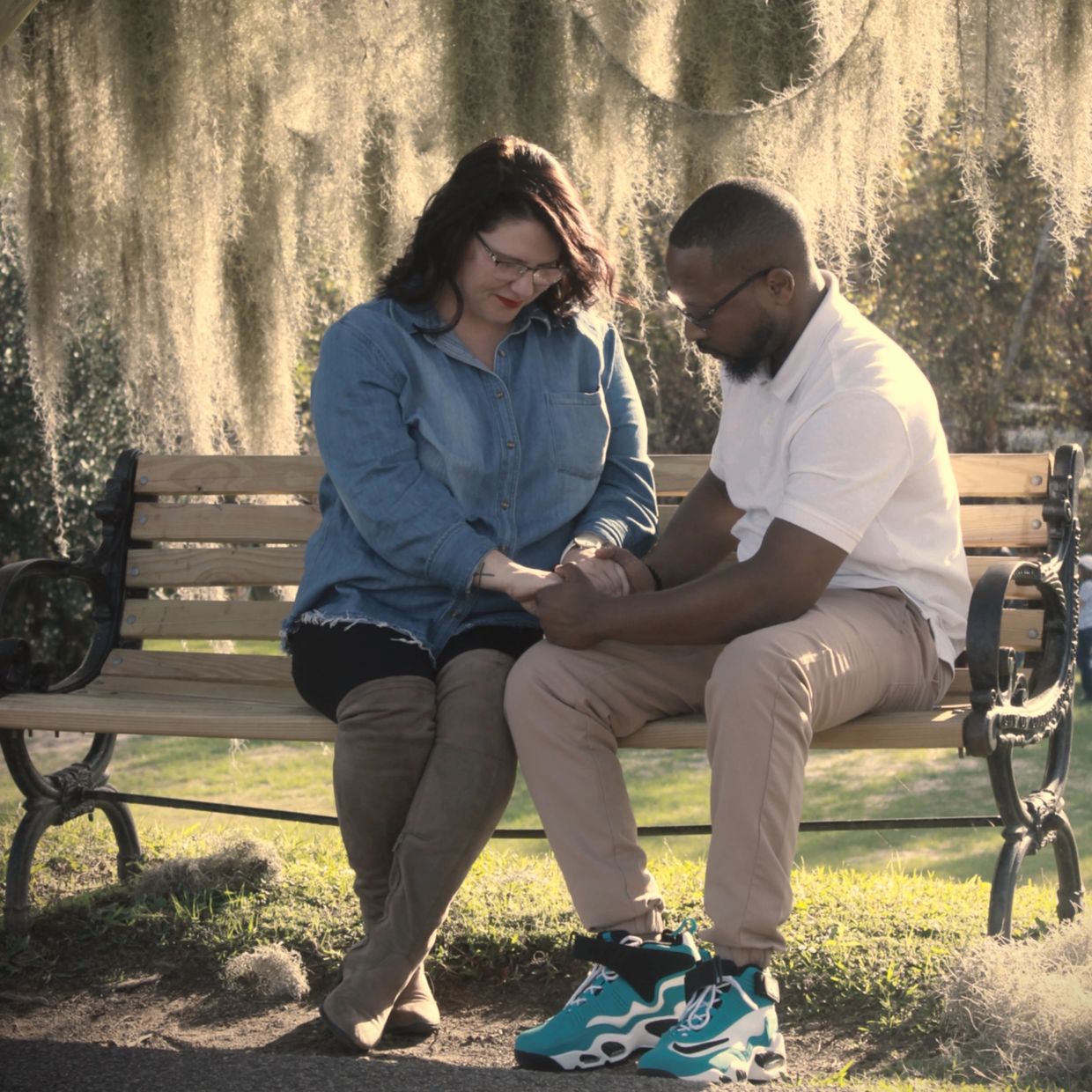 Couple sharing a tender moment holding hands on a park bench.
