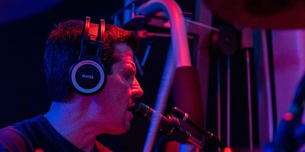 Man wearing headphones playing a saxophone.