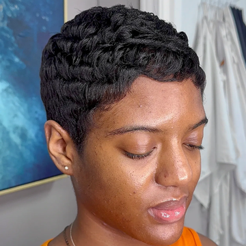 Close-up of a woman with short, styled hair and glowing skin.