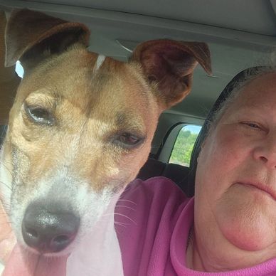 A close-up selfie of a person and a dog inside a car.