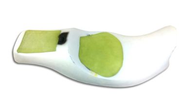 White ceramic spoon with green and black paint patches.
