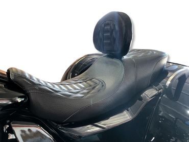 Close-up of a black, textured motorcycle seat with backrest.