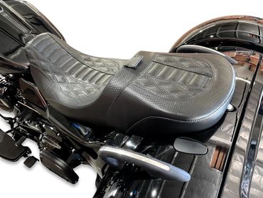 Close-up of a textured black motorcycle seat on a shiny black bike.