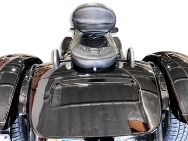 Close-up of a black leather motorcycle seat with backrest and side mirrors.