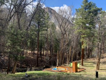 Hot spring pool next to Chalk Creek, tall pine trees and Chalk Cliffs in background