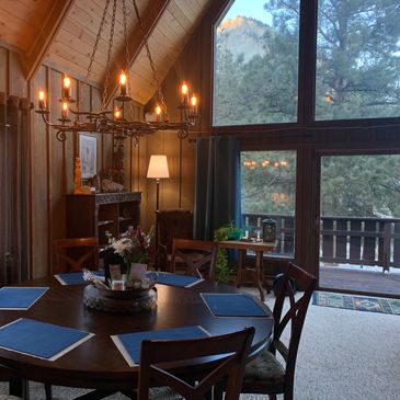 Round wood dining table with six chairs in dining area, large tall windows