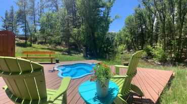 Summer picture of bright green chairs on deck, flowers, hot spring pool and pine trees
