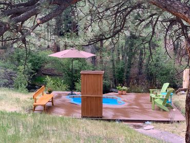 Overcast day with hot spring pool, shade umbrella and tree in foreground