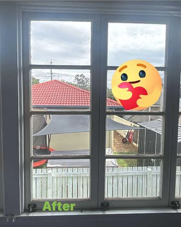 View through a clean window showing a backyard with a red roof and white fence.