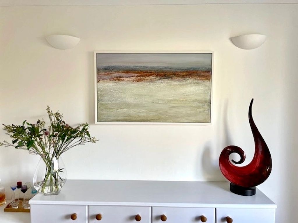 An abstract seascape painting with warm sandy tones and sunset colours in a living room setting