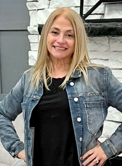 Smiling woman with blonde hair wearing a denim jacket and black shirt.