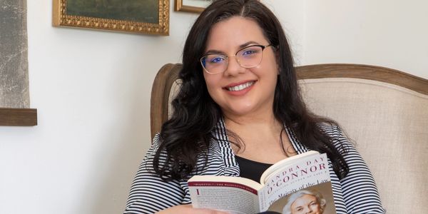 Picture of a remote senior immigration paralegal holding a book.