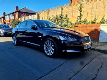 Sleek black Jaguar sedan parked on a residential street.