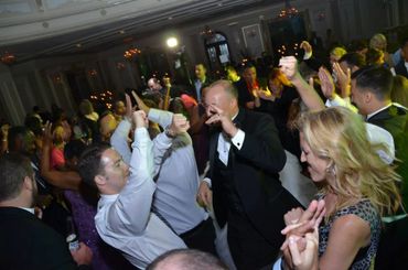People joyfully dancing at a lively indoor party or wedding reception.