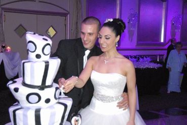 Bride and groom cutting a uniquely designed wedding cake with black and white patterns.