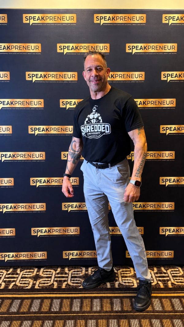 Man posing in front of a Speakpreneur backdrop.