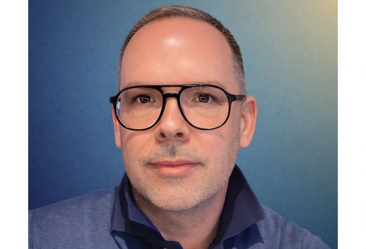 Man with glasses and blue shirt against a blue background.