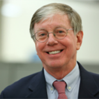 Smiling elderly man in glasses and suit.
