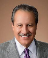 Smiling man in a gray suit with a purple tie.