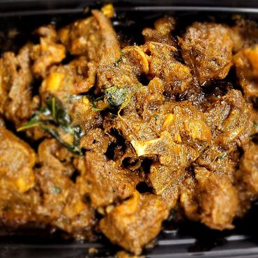 Spicy cooked meat pieces in a dark container.