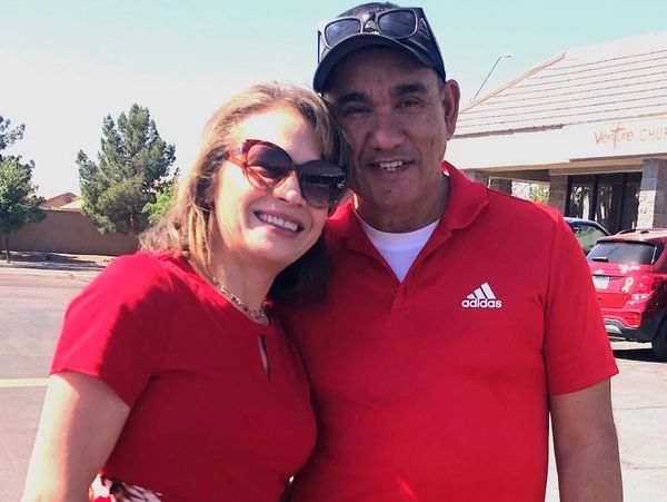 Smiling couple in red shirts posing outdoors.