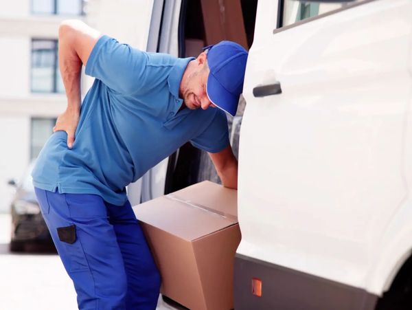 Delivery man experiencing back pain lifting box.