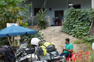 Two loaded adventure motorcycles parked near a roadside cafe with people sitting outside.